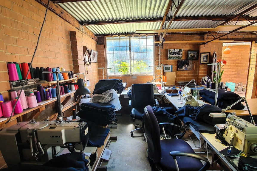 A room with well-lit windows and it has three sewing machines on tables