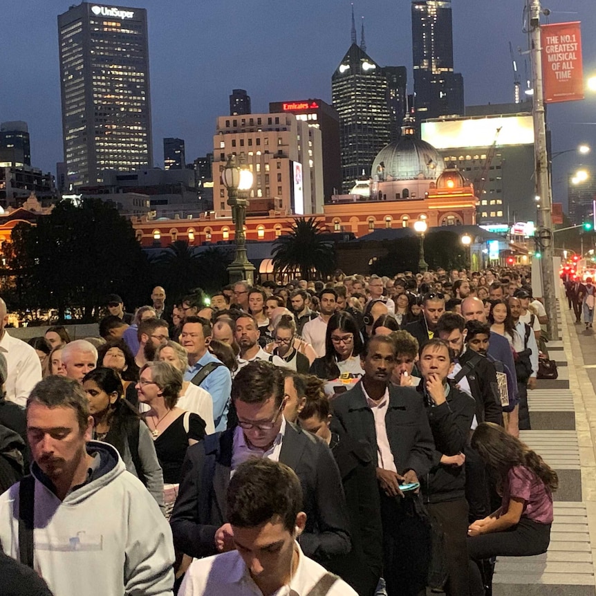 Passengers queue across Princes Bridge in Melbourne.