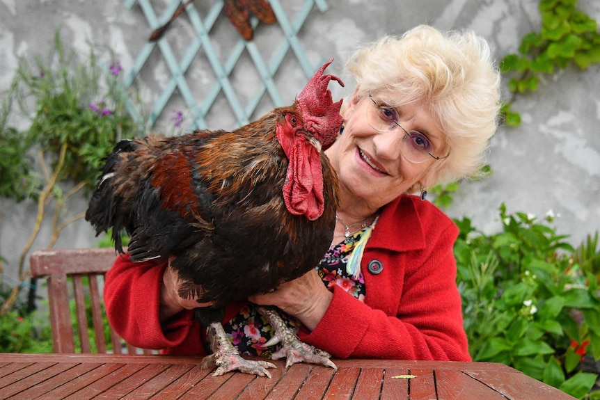 Corinne Fesseau poses with her rooster Maurice in her garden.