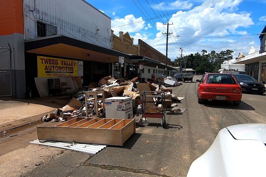 Damaged household goods and other debris on the street in front of a Tweed Valley Automotive sign on a shop.