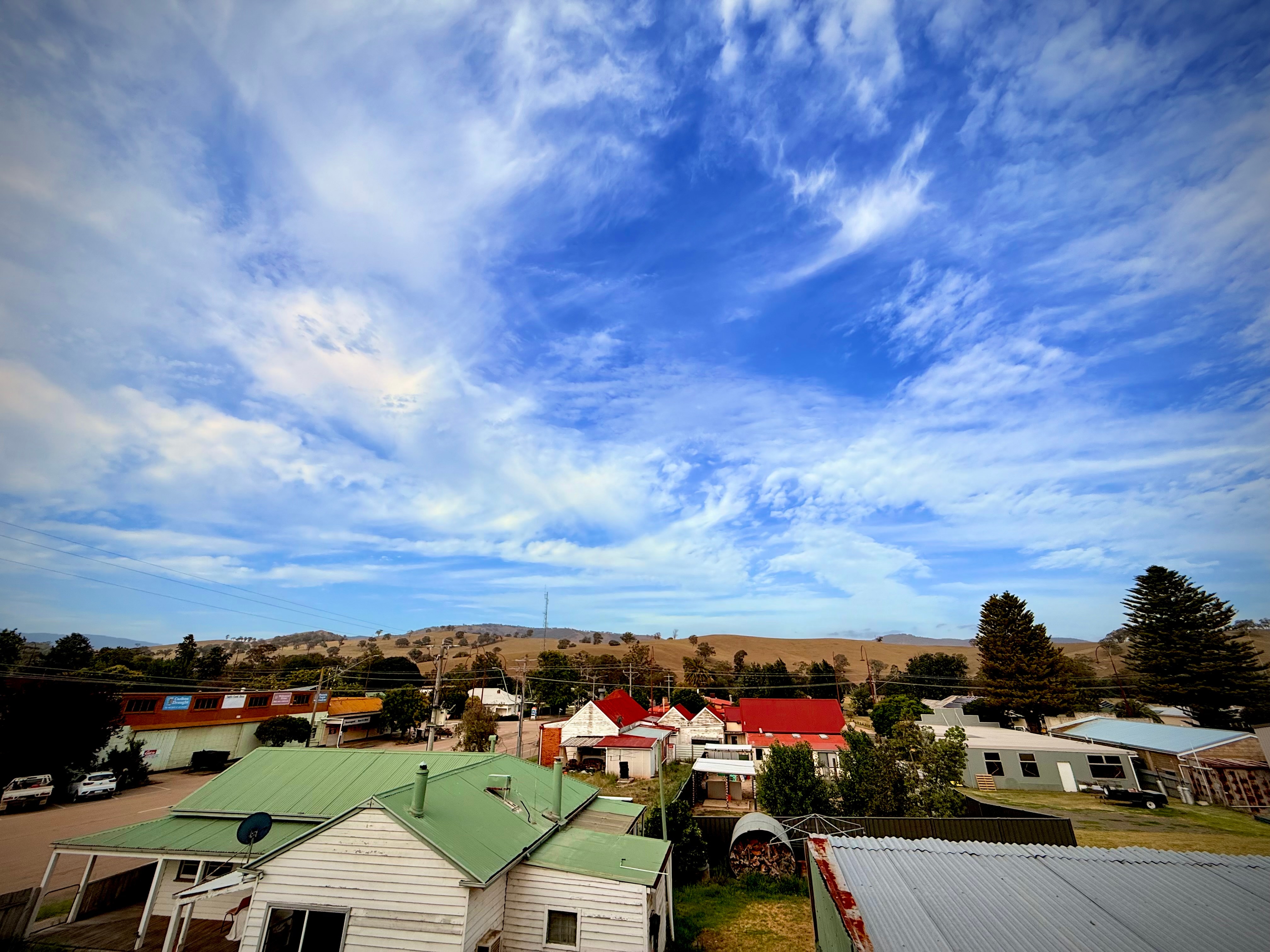 বিশাল নীল আকাশের ছবি, পটভূমিতে পাহাড় এবং দালান ও বাড়ির ছাদ। 