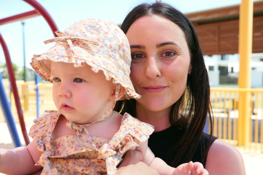 Janita and her baby standing near a playground.