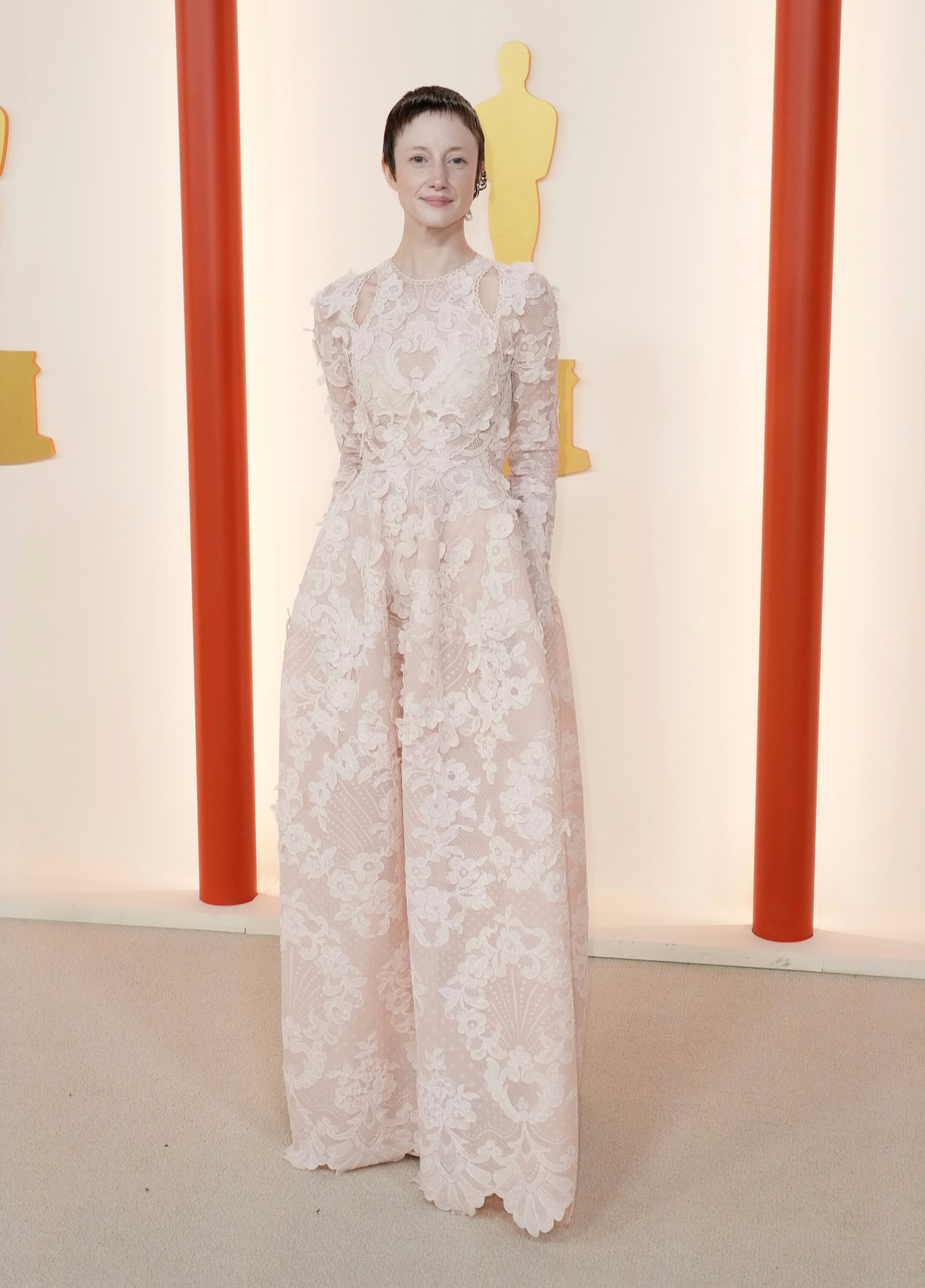 Andrea Riseborough wearing a long-sleeved, floor-length lacey beige gown