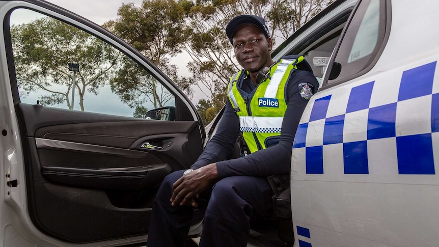 Victoria Police Constable Kur Thiek sitting inside a police car with the door open.