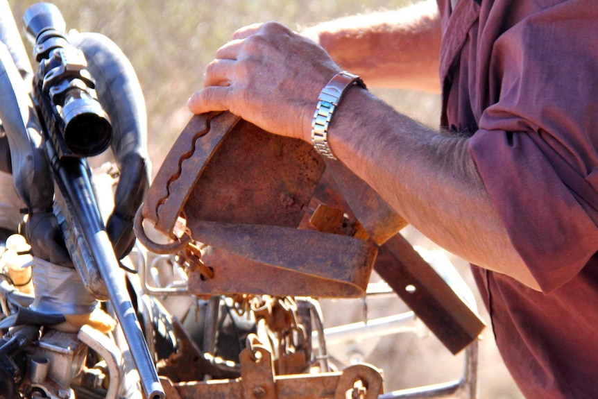 Don Sallway removes a trap from the front of his motorbike.