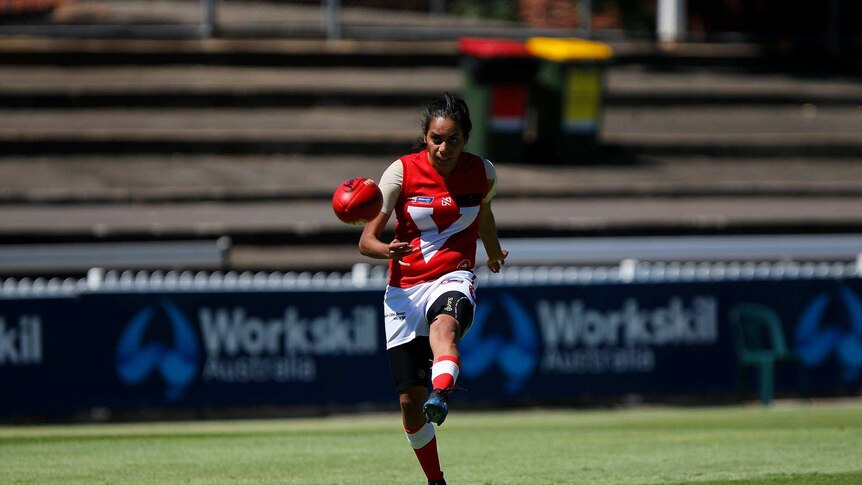 Angle Vale Football Club player Margaret Varcoe kicks a football.