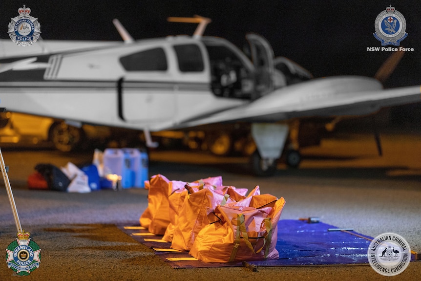 large yellow bags laid out on the tarmac in front of a light plane