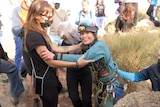 A crowd of people surround a woman in mountaineering gear