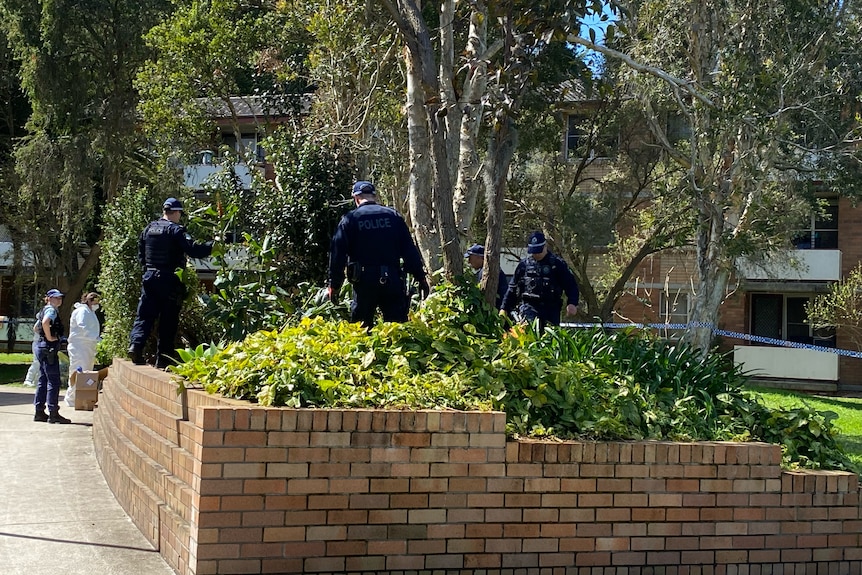 Multiple police officers walking in a garden.