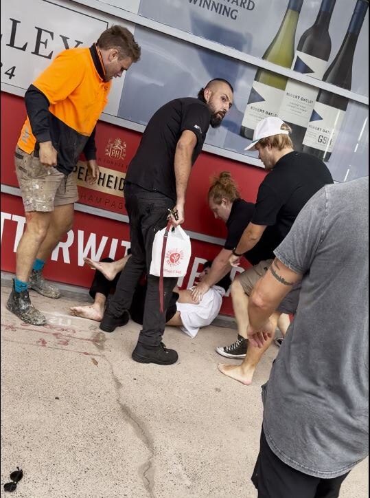 A man lies on the ground with five men around him
