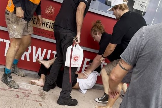 A man lies on the ground with five men around him