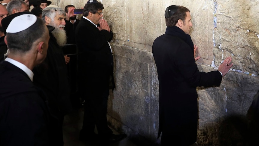 French President Emmanuel Macron standing against a holy wall in Israel.