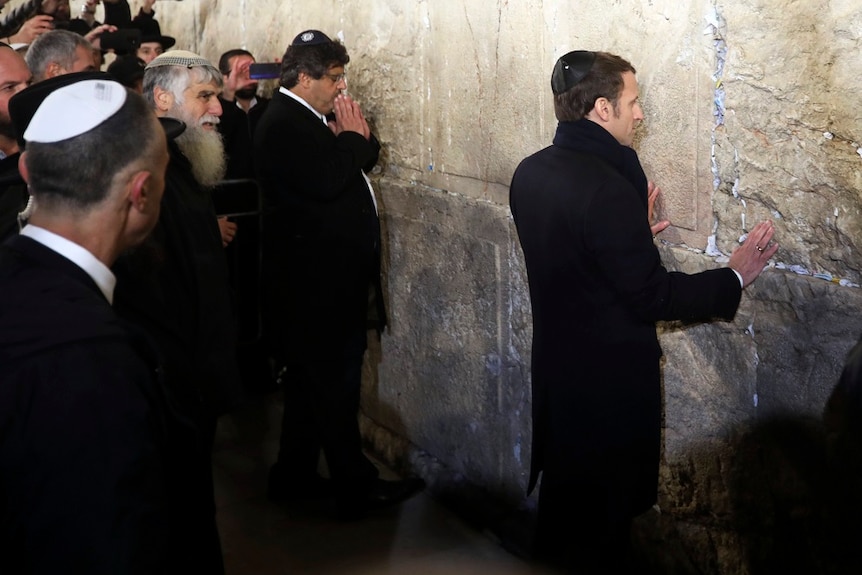 French President Emmanuel Macron standing against a holy wall in Israel.