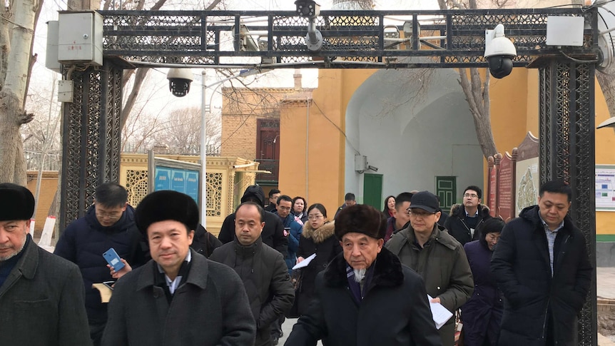 People pass under security cameras while leaving a mosque in Xinjiang province.