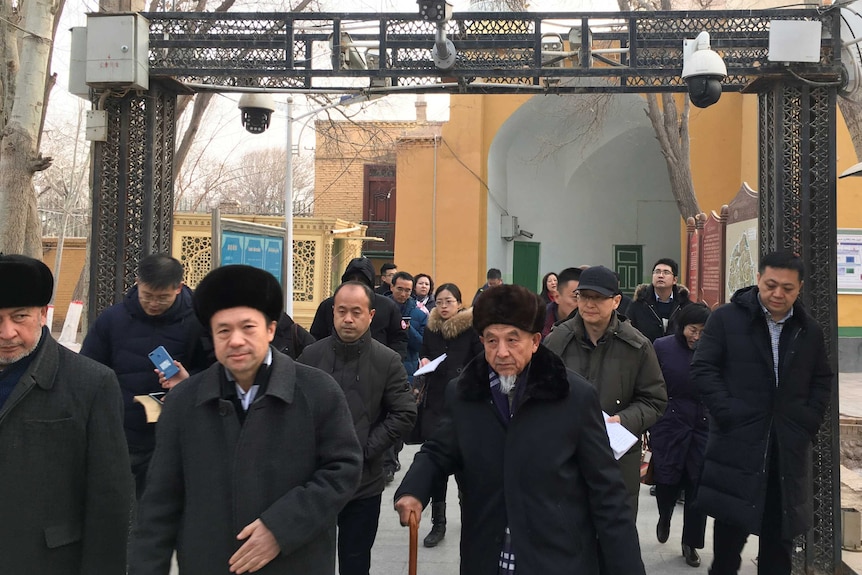 People pass under security cameras while leaving a mosque in Xinjiang province.