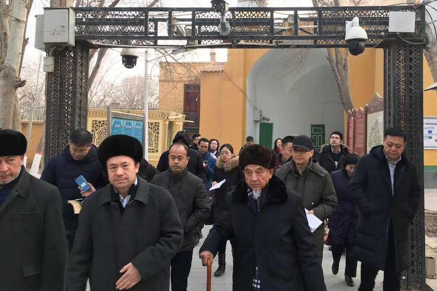 Imams and government officials pass under security cameras at a mosque in Kashgar, China.