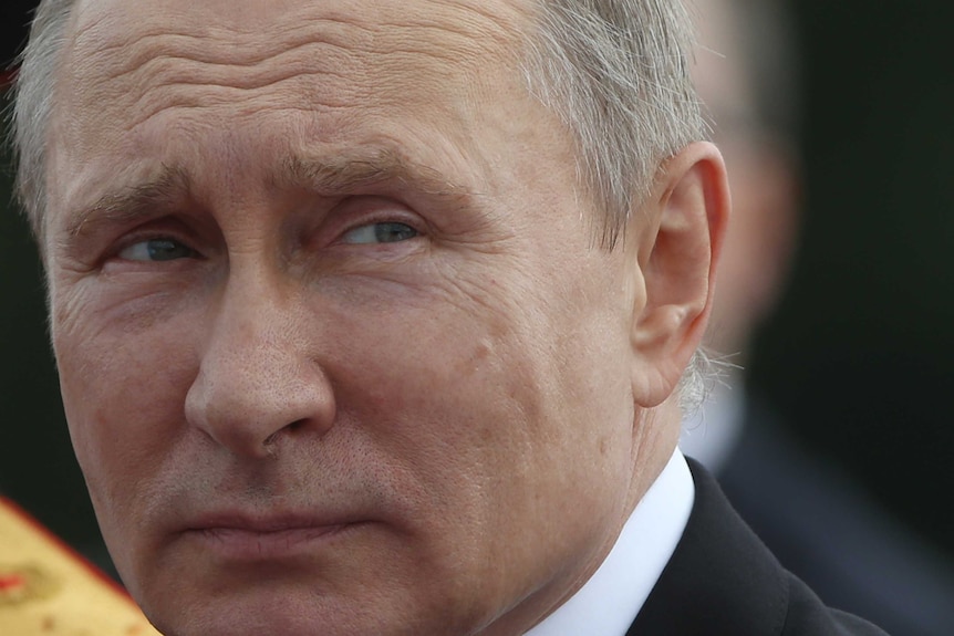 A close-up of Russian President Vladimir Putin glancing to one side.