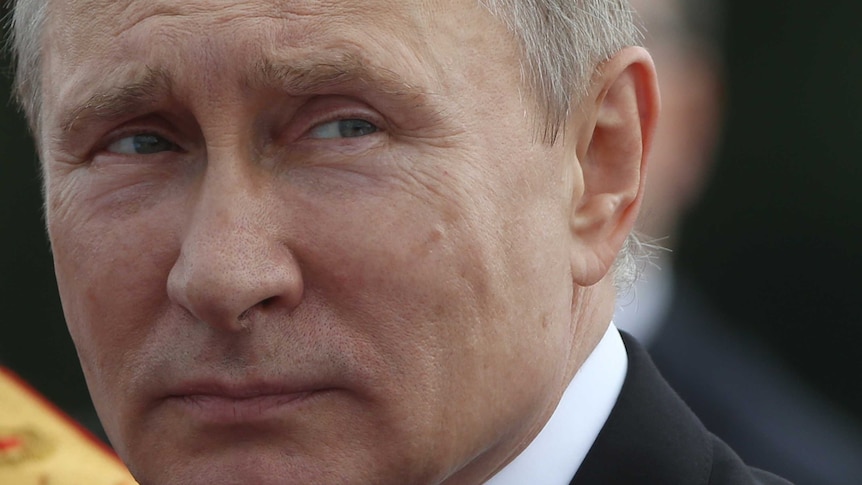 A close-up of Russian President Vladimir Putin glancing to one side.