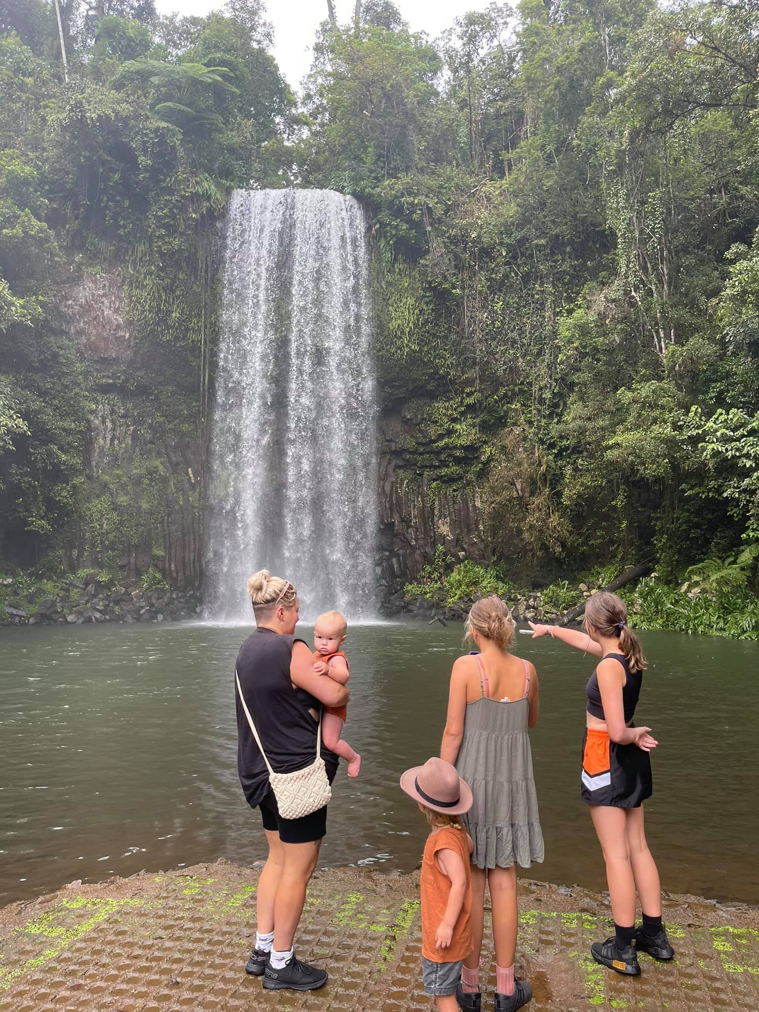 A family pose together for a photo at a waterfall.