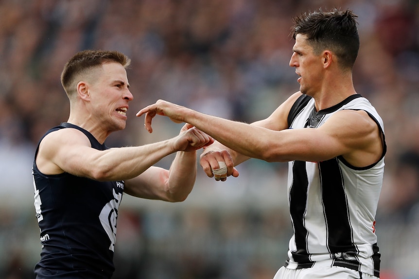 A Carlton AFL player scuffles with a Collingwood opponent. 