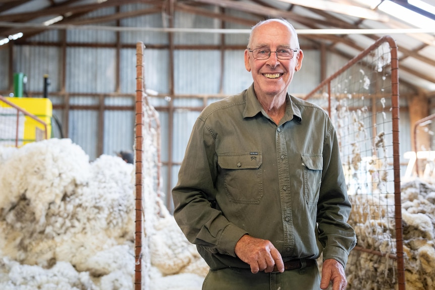 A man in a work shirt standing in a she smiling.