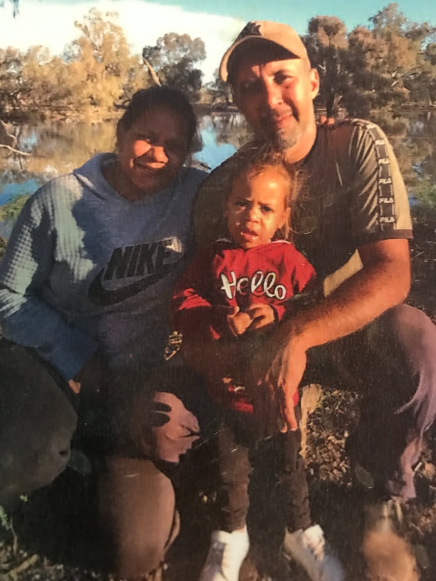 Indigenous man and woman with a young child, during sunset.