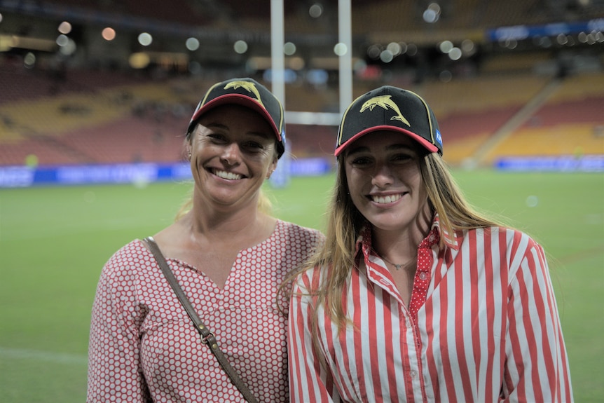 A teenager and her mother stand in front of an NRL stadium
