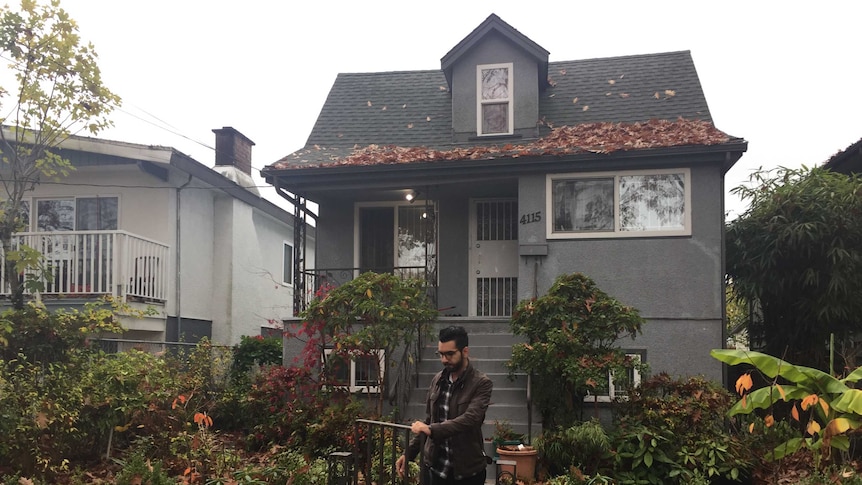 A man walks out the front gate of a small home.