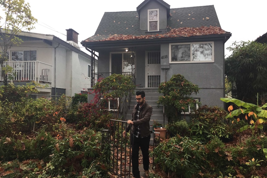 A man walks out the front gate of a small home.