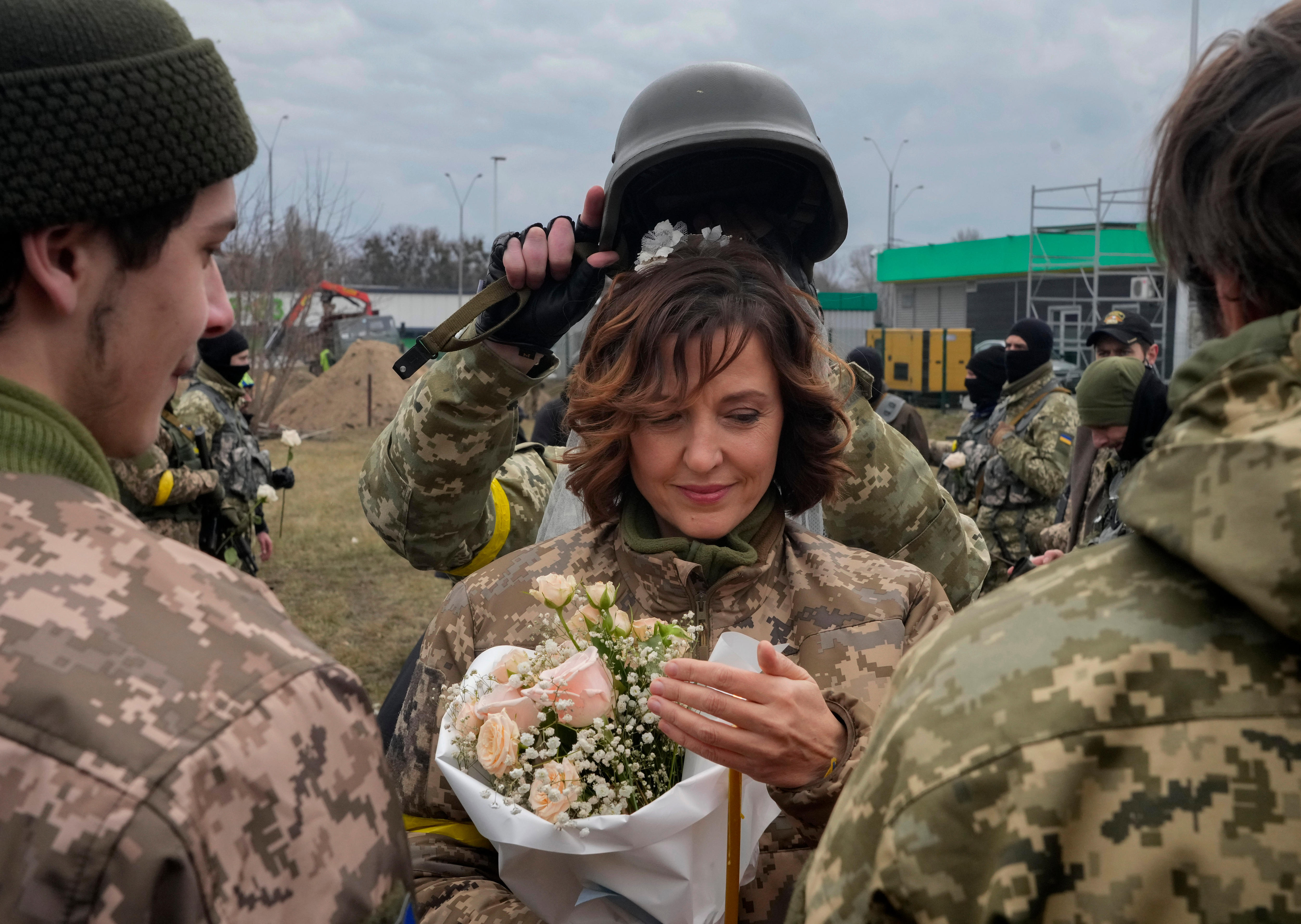 A soldier holds a helmet as a wedding crown over the bride's head