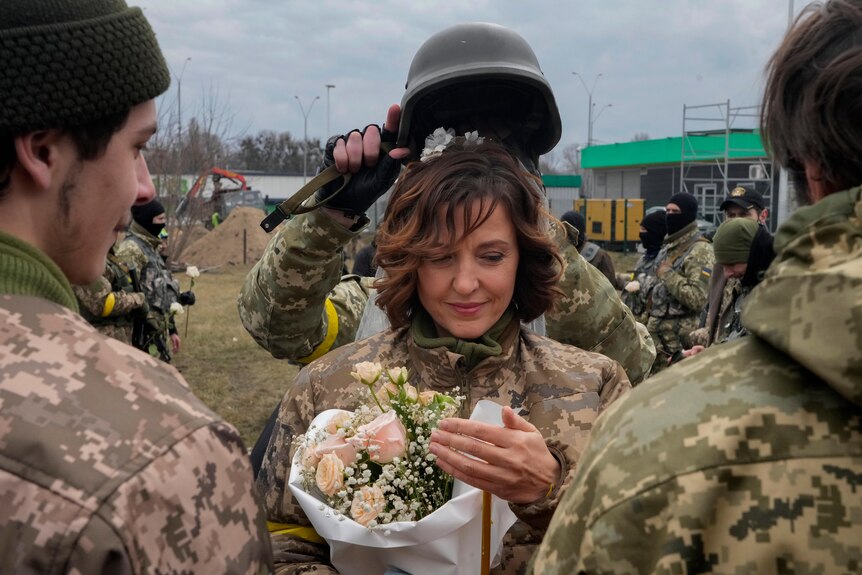 A soldier holds a helmet as a wedding crown over the bride's head