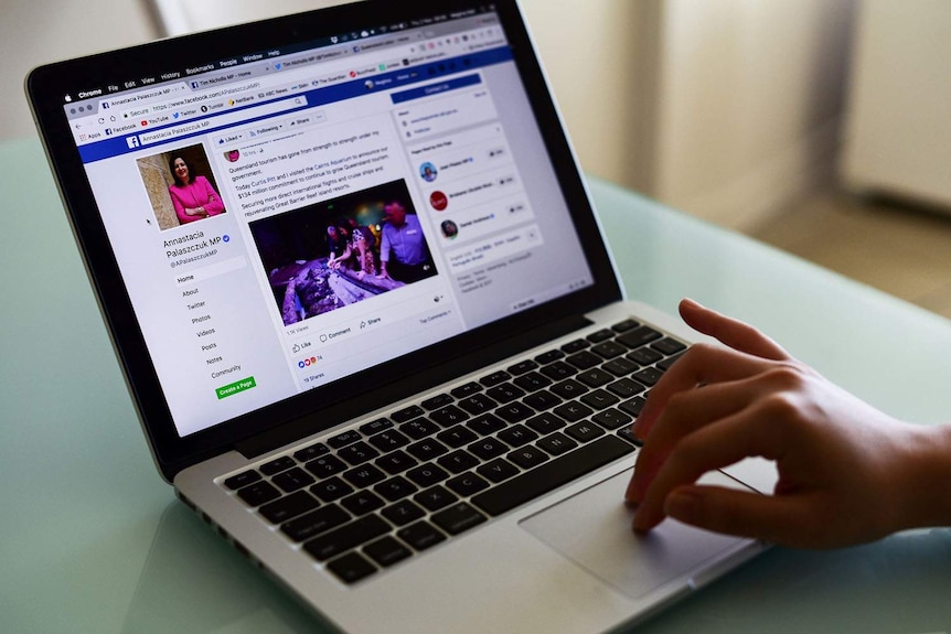 Open laptop with a person's hand in view looking at the Facebook page of Queensland MP Annastacia Palaszczuk.