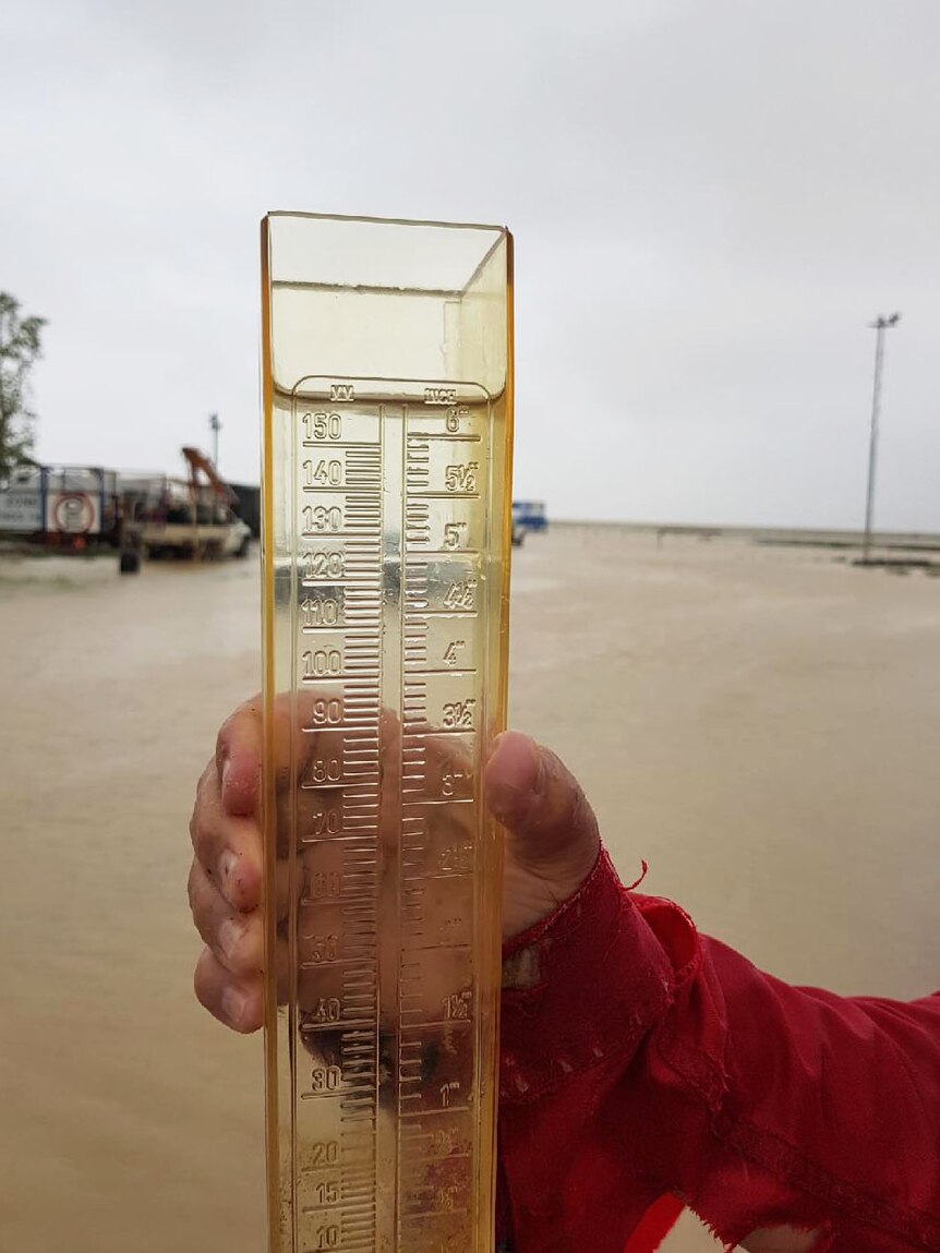 Farmer holds up full rain gauge after heavy falls at Julia Creek March 5 2018