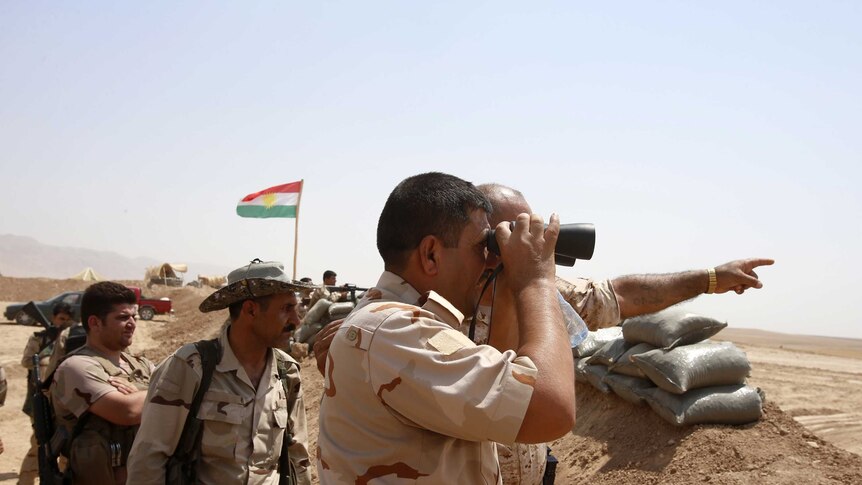Kurdish Peshmerga fighters stand guard against Islamic State insurgents in August.