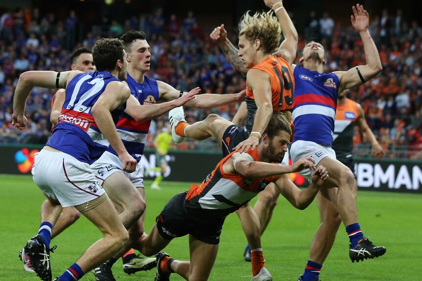 Western Bulldogs and GWS players on the field in a twilight preliminary final match.