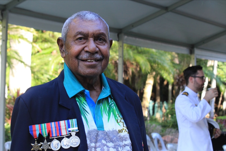 A man wearing medals smiles.