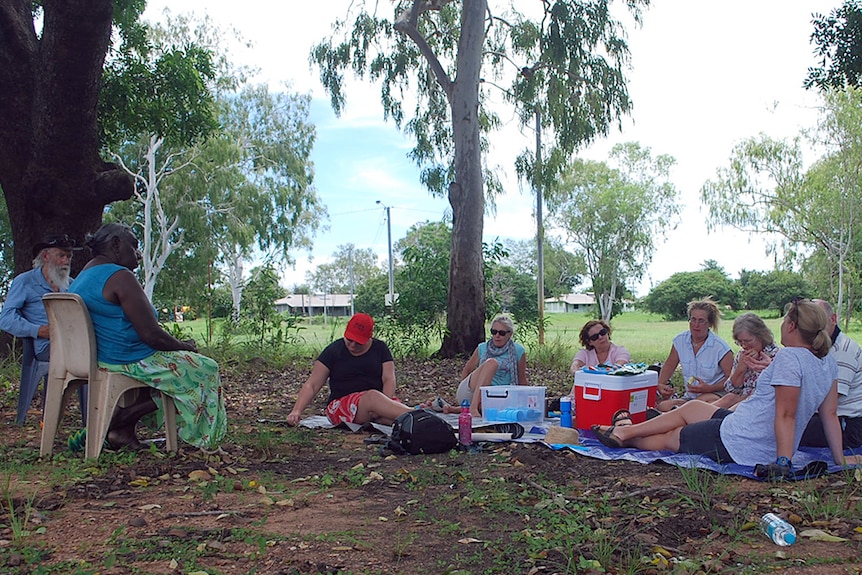 Miriam Rose Baumann sits under a tree with people participating in one of her cultural connection tours in Nauiyu.