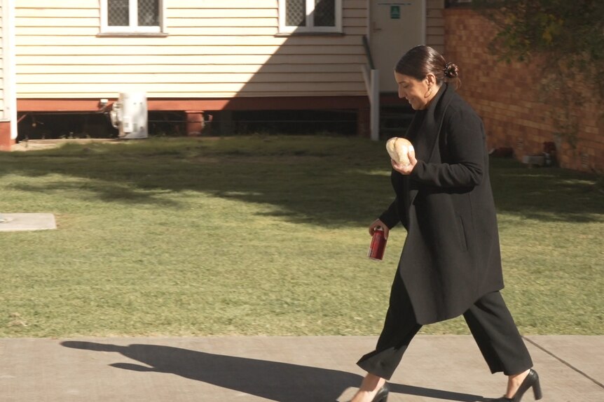 A woman wearing black walks back into court.