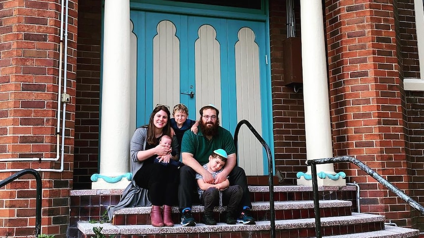 A family sit on the steps of an ornate building