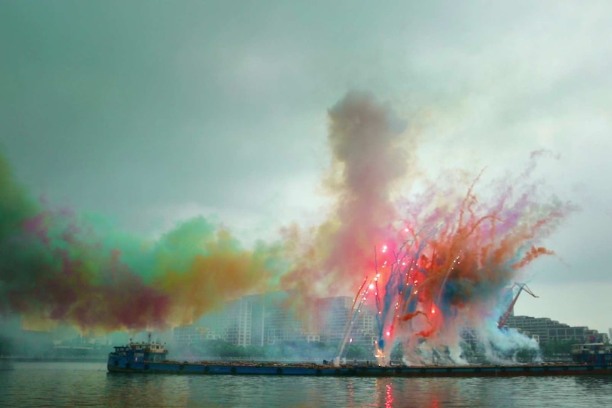 Colourful smoke display against cloudy sky.