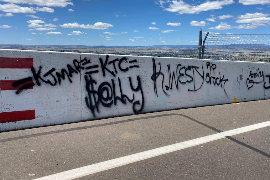Spray painted graffiti on a concrete race wall which looks out over Bathurst.