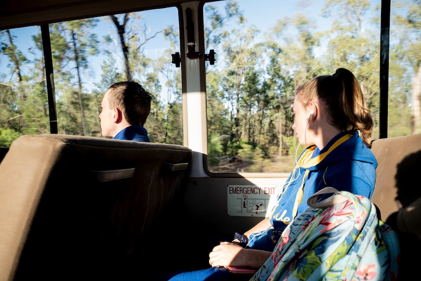 Students look out the bus window with headphones on.