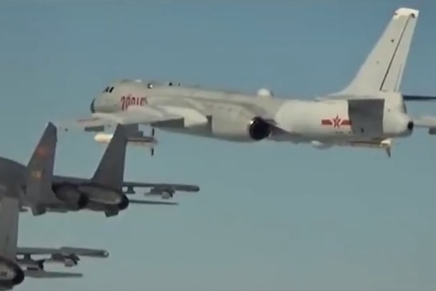 China's H-6K bomber, as seen in a propaganda film released by the PLA. It is light grey with a red star at the rear.