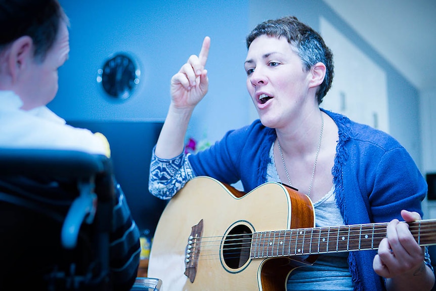 music therapist with guitar singing to a client