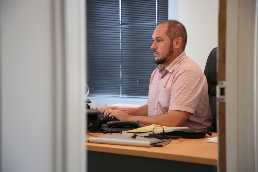 A man sits in his office typing on a computer.