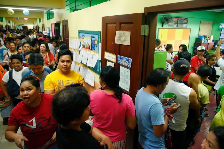People queue up outside a polling precinct to vote in the Philippine midterm elections.