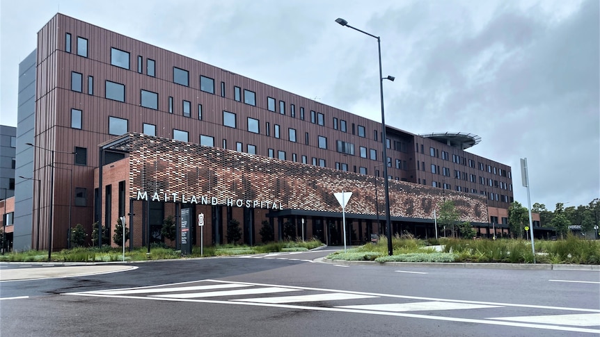  A six-storey, rust coloured hospital building on a cloudy day.