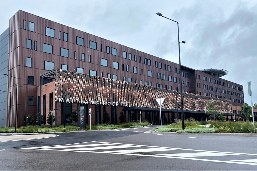  A six-storey, rust coloured hospital building on a cloudy day.