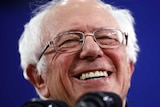 Bernie Sanders smiling at a microphone