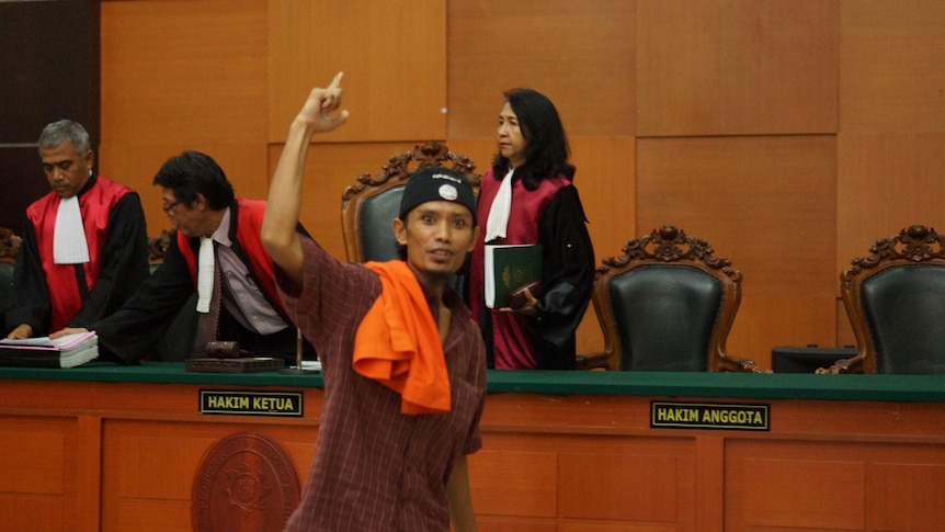 Juhanda points to the sky as he walks through the courtroom.